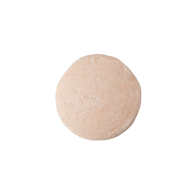 A round, pink coloured face wash bar. 
