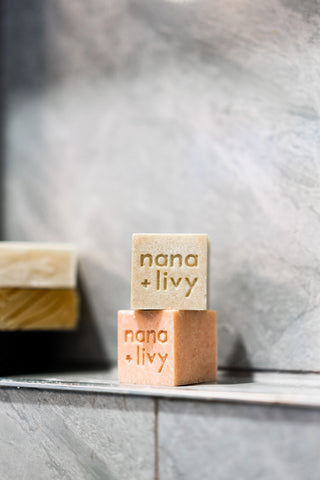 Nana + Livy green and pink soap blocks stacked on shower niche without packaging