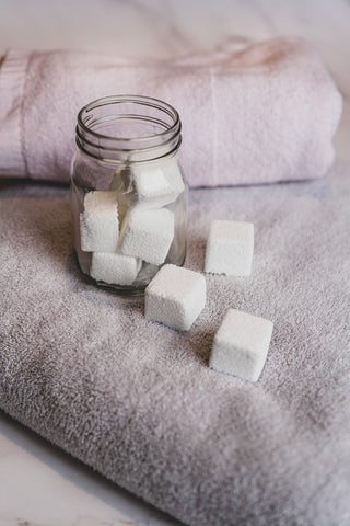 White powdered tablets in an opened mason jar and scattered on top of a grey folded towel