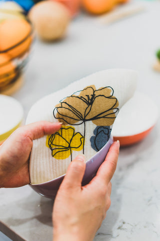 Pair of hands using Swedish dishcloth to wipe bowls