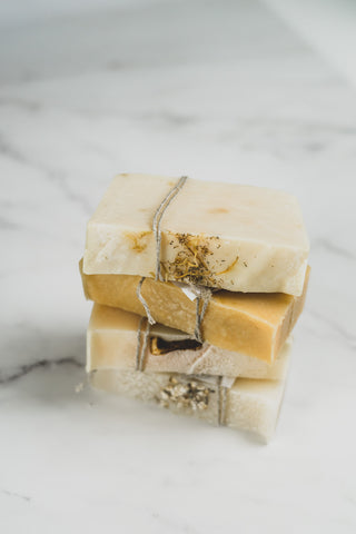 Four stacked bars of handcrafted soaps in ivory and orange colours. 