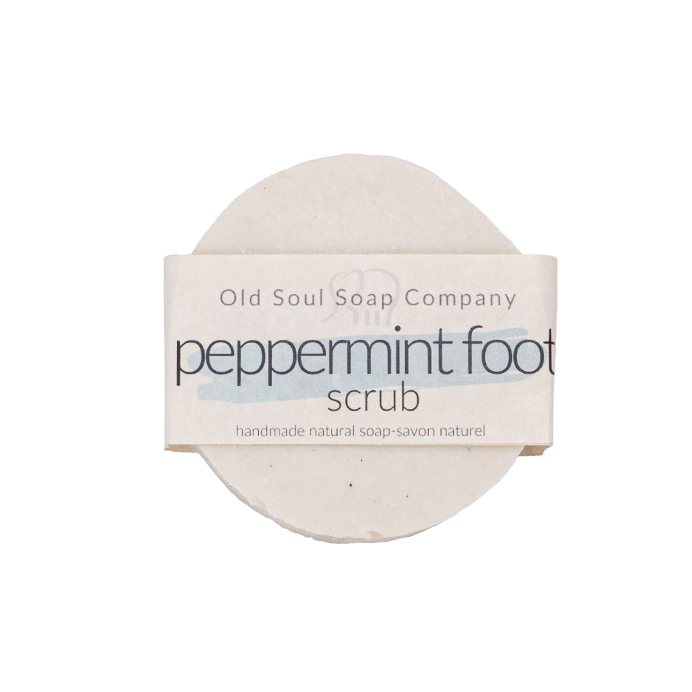 A round white bar with minimal paper packaging labelled Peppermint Foot Scrub by Old Soul Soap Company.