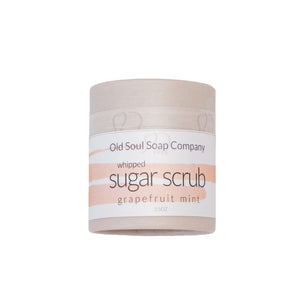 A cylindrical paper-tube light grey container labelled as Whipped Sugar Scrub in Grapefruit Mint scent, by company Old Soul Soap Company.