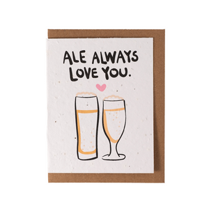A white greeting card laying over top of a kraft envelope. The card contains the text Ale Always Love You and an image of two pints of ale.