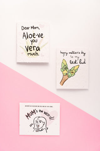 Three Mother's Day cards laid on a white and pink background.
