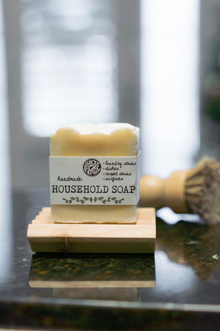 Two Acre Farm's household soap on a soap dish sitting on a kitchen counter with a dish scrub brush